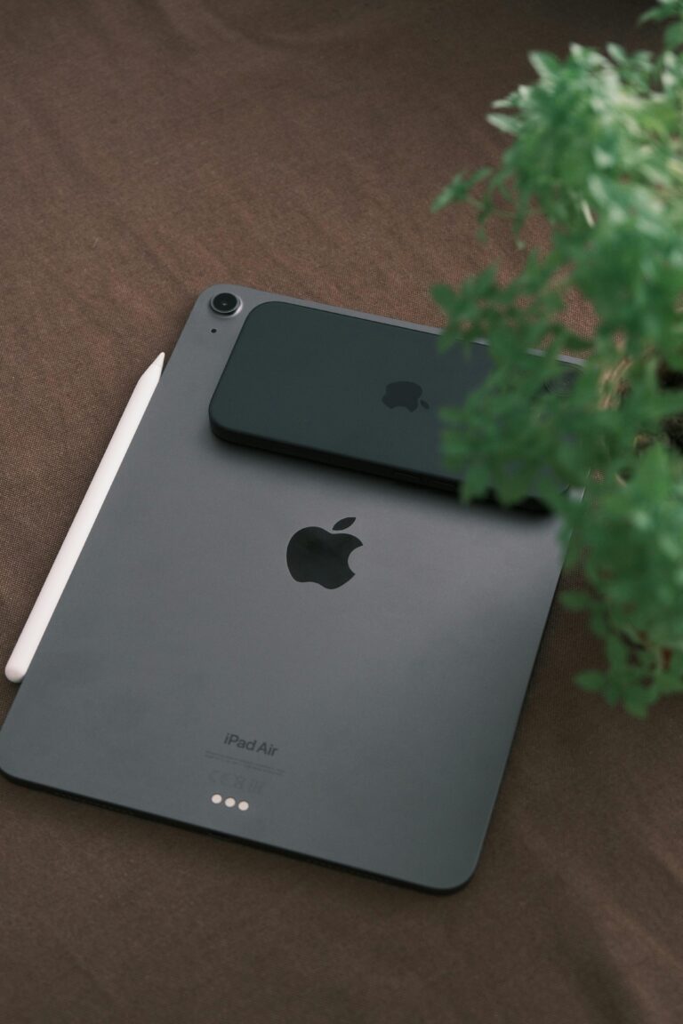 Minimalist tech setup featuring a tablet, smartphone, and stylus on a wooden surface.